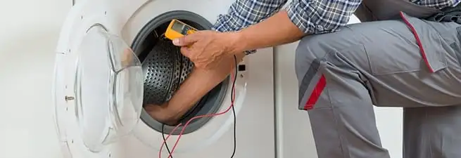 Dryer repair technician inspecting and repairing a clothes dryer in Manchester, NH