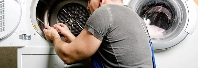 Dryer repair technician fixing a clothes dryer drum in Manchester, NH