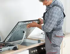 Appliance repair technician installing a built-in cooktop in Manchester, NH