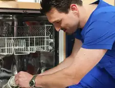 Dishwasher repair technician inspecting and servicing an open dishwasher in Manchester, NH