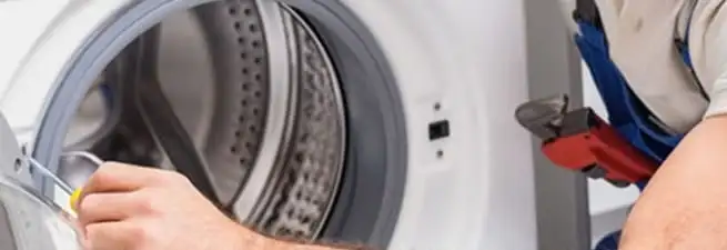 Appliance technician repairing a clothes dryer drum and internal parts in Manchester, NH