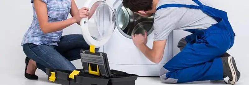 Washer repair technician inspecting a front-load washing machine with tools in Manchester, NH