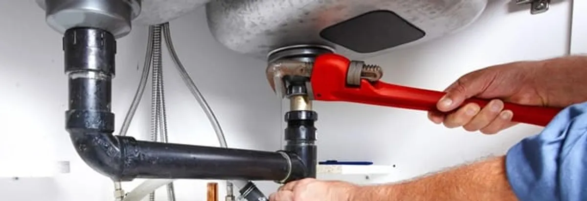 Garbage disposal repair technician tightening the sink drain and disposal connection in Manchester, NH