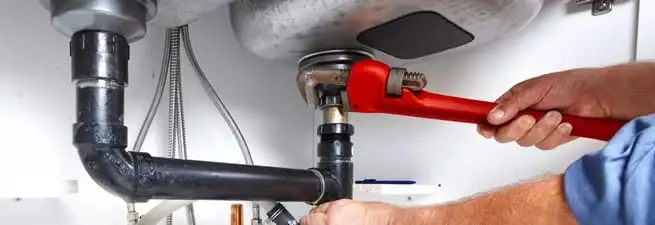 Garbage disposal repair technician tightening the sink drain and disposal connection in Manchester, NH