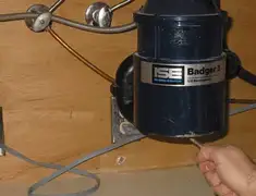 Garbage disposal repair technician tightening the mounting ring under a sink in Manchester, NH
