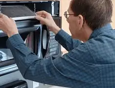 Appliance repair technician replacing a microwave vent filter in Manchester, NH