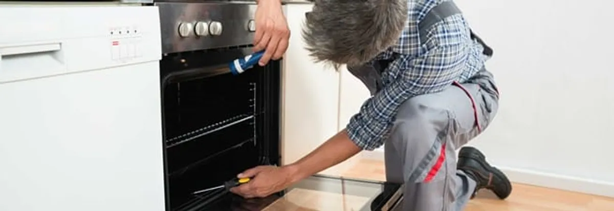 Oven repair technician inspecting and servicing an electric oven in Manchester, NH