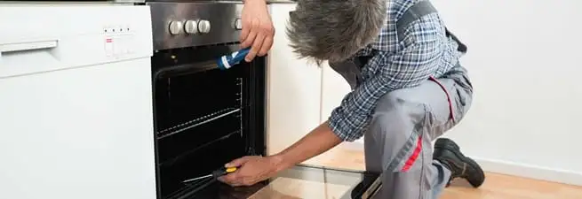 Oven repair technician inspecting and servicing an electric oven in Manchester, NH