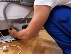 Appliance repair technician fixing refrigerator water line and connections in Manchester, NH