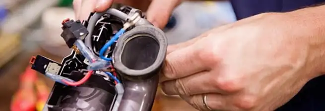 Vacuum repair technician reconnecting wiring and components in Manchester, NH