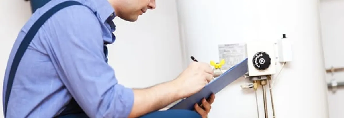 Water heater repair technician inspecting the unit and recording service notes in Manchester, NH