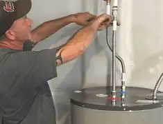 Water heater repair technician tightening supply line connections in Manchester, NH