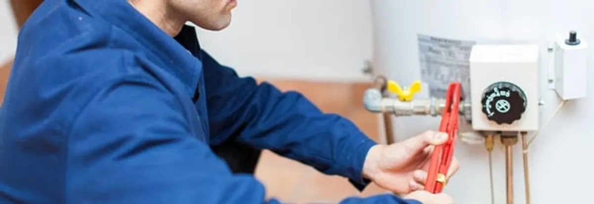 Water heater repair technician adjusting the temperature control and gas valve in Manchester, NH